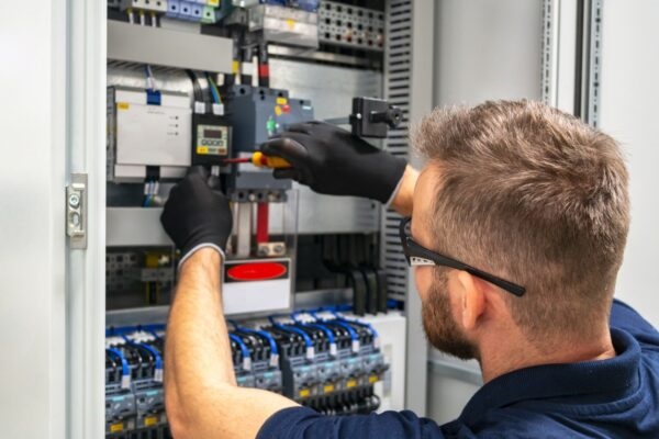 Photo of an electrician working at distribuition board.